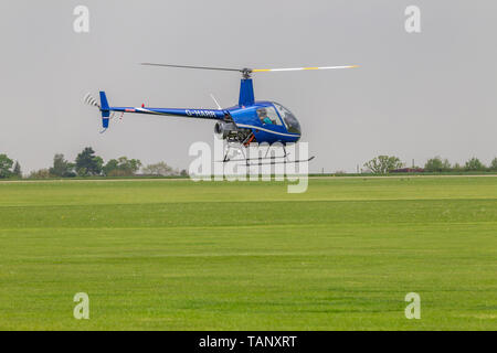 Un hélicoptère Robinson R-22 Beta voler contre un ciel sombre au cours de l'après-midi à Sywell Northamptonshire, l'aérodrome Banque D'Images