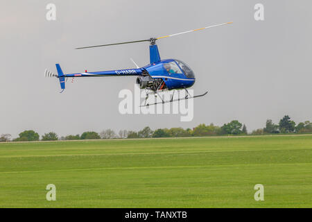 Un hélicoptère Robinson R-22 Beta voler contre un ciel sombre au cours de l'après-midi à Sywell Northamptonshire, l'aérodrome Banque D'Images