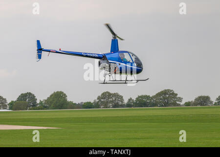 Un hélicoptère Robinson R-22 Beta voler contre un ciel sombre au cours de l'après-midi à Sywell Northamptonshire, l'aérodrome Banque D'Images