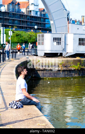 L'homme aux yeux clos et les paumes sur ses genoux en méditant au Bristol Harbourside, Princes Wharf, UK Banque D'Images