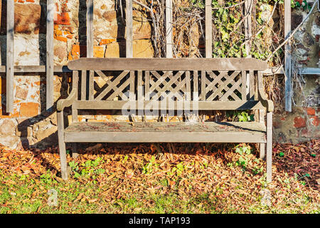 Un banc en bois est à un mur de pierre au soleil. Banque D'Images