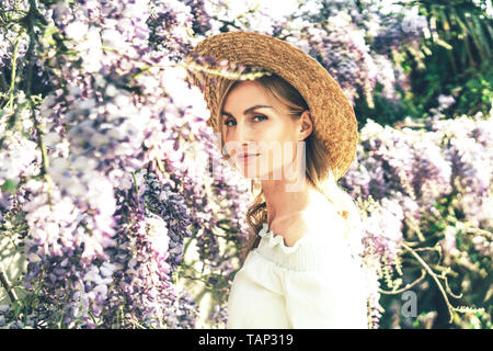 Portrait d'une belle femme blonde caucasienne, European style rétro, romantique, printemps la floraison des glycines, de magnifiques grappes de fleurs. Banque D'Images