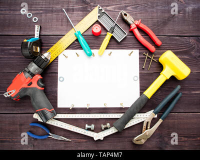 L'outil s'appuyant sur le fond de bois autour de la feuille de papier blanc Banque D'Images