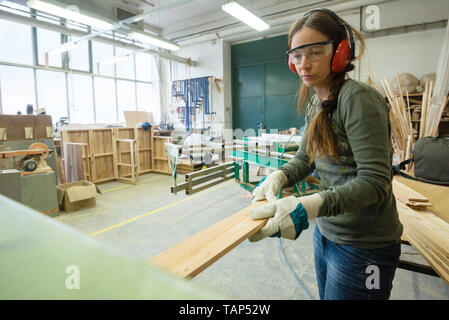 Jeune femme planche en bois à l'atelier de transformation Banque D'Images