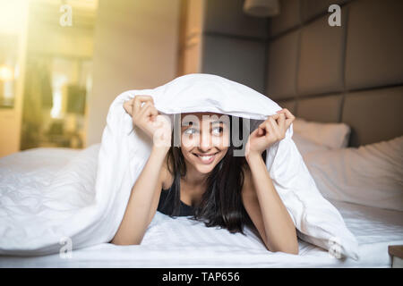 Jeune femme se reposant sous une couette dans son lit Banque D'Images