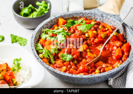 Ragoût de haricots vegan avec les tomates dans une casserole à fond blanc. La nourriture végane concept. Banque D'Images