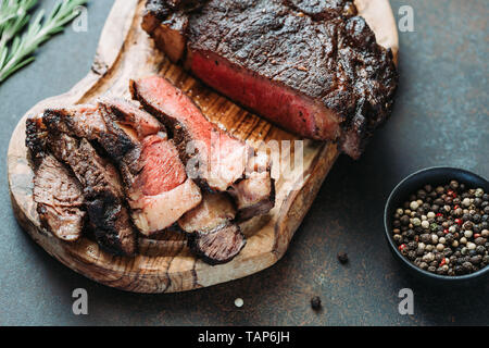 Dry-aged en pavé de boeuf Tomahawk sur planche de bois avec des épices. Close-up, dîner concept. Banque D'Images