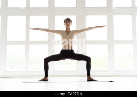 Yogi Young attractive woman practicing yoga concept, assis dans l'exercice Malasana, Garland, travailler, le port des vêtements de sport, pleine longueur Banque D'Images