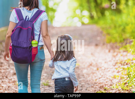 Jeune mère détient sa petite fille main dans la forêt.Happy mother and daughter moments avec amour et émotion naturelle.Photo de la mère et la fille ayant rendez-vous Banque D'Images