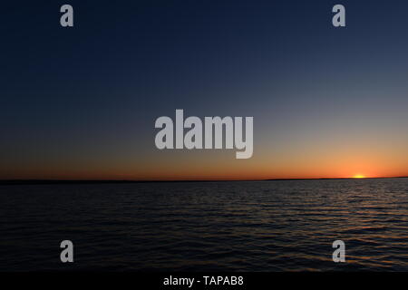Coucher du soleil dans le ciel bleu à l'horizon au-dessus de l'eau du lac Banque D'Images