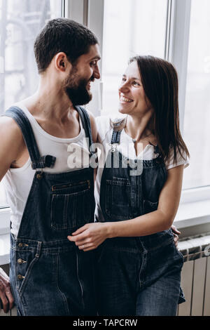 Couple debout près de la fenêtre et s'étreindre les uns les autres et sourire Banque D'Images