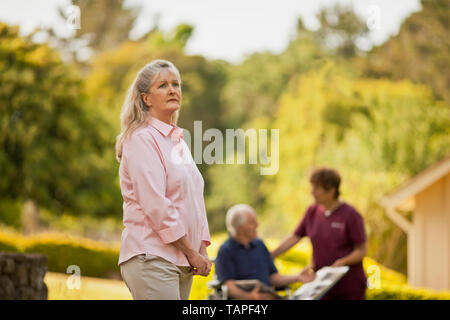 Concerné senior woman standing dans son arrière-cour. Banque D'Images