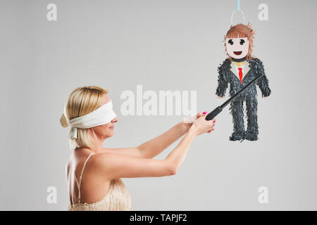 Photo de femme homme frapper pinata sur fond gris Banque D'Images