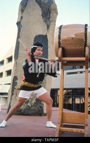 Un homme japonais taiko drumming effectue dans Little Tokyo, le coeur historique de la communauté nippo-américaine dans le centre-ville de Los Angeles, Californie, USA. Jouant du tambour Taiko est puissant, fort et vite, et implique des mouvements chorégraphiés qui beaucoup d'identifier avec les arts martiaux japonais scène extérieure de ce batteur est le Japanese American Cultural & Community Centre (JACCC) Plaza dispose que basalte monumental des sculptures de l'artiste de renommée mondiale, Isamu Noguchi. Intitulée "Pour l'Issei, son oeuvre sculpté des Noguchi en 1980 comme un hommage à la première génération de Japonais qui ont immigré en Amérique latine Banque D'Images