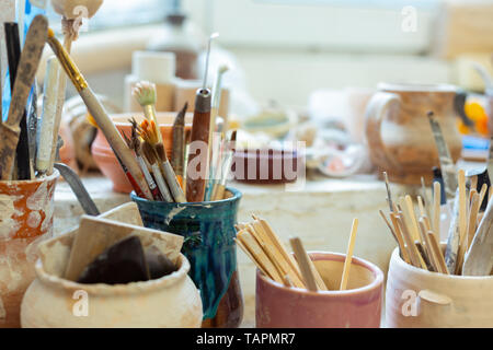 Matériaux étant organisés. Pile de pinceaux d'un séjour avec des outils en bois et en métal et d'être couverts dans l'argile Banque D'Images