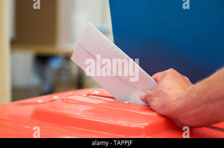 Hambourg, Allemagne. 26 mai, 2019. ILLUSTRATION - l'assistant d'une élection met le bulletin de vote d'un électeur dans une urne à un bureau de scrutin pour l'élection d'euros dans une boîte de scrutin. Du 23 mai au 26 mai, les citoyens de 28 États de l'Union européenne éliront un nouveau parlement. Crédit : Daniel Bockwoldt/dpa/Alamy Live News Banque D'Images