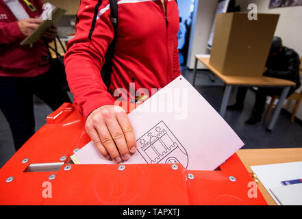 Hambourg, Allemagne. 26 mai, 2019. Dans un bureau de vote, l'électeur place son bulletin de vote pour les élections européennes et les élections à l'assemblée de district dans la boîte de scrutin. Du 23 mai au 26 mai, les citoyens de 28 États de l'Union européenne éliront un nouveau parlement. Crédit : Daniel Bockwoldt/dpa/Alamy Live News Banque D'Images