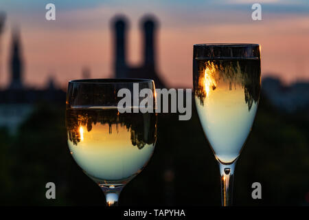 26 mai 2019, Bavaria, Munich : au coucher du soleil, deux verres de vin blanc debout sur le mur de l'allée du parlement bavarois en face de la skyline de la capitale bavaroise. Dans l'arrière-plan vous pouvez voir les tours de la vieille pierre', l'hôtel de ville (M) et l'église Frauenkirche (r). Photo : Peter Kneffel/dpa Banque D'Images