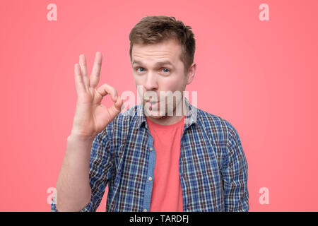 Cheerful young man showing ok sign. Studio shot Banque D'Images