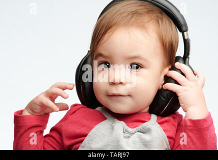 Baby Girl écouter de la musique avec des écouteurs sur isolé sur fond blanc Banque D'Images