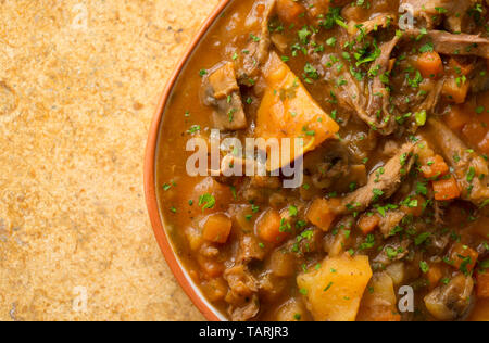 Une assiette de ragoût de venaison maison faite à partir de la viande du gibier mijoté d'os qui ont été mijotée dans une cocotte avec les légumes, les champignons et les herbes pour Banque D'Images