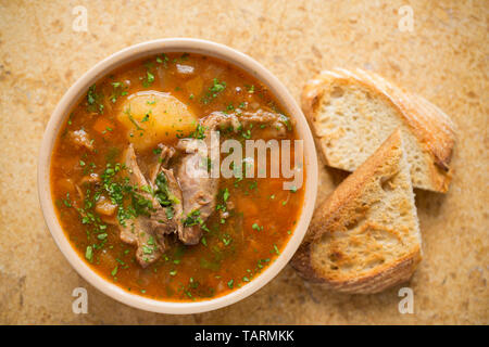 Un bol de soupe de gibier maison faite à partir de la viande du gibier mijoté d'os qui ont été mijotée dans une cocotte avec les légumes, les champignons et les herbes pour s Banque D'Images