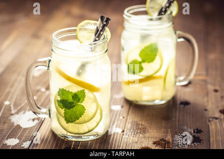 Mojito Cocktail frais froid limonade avec de la glace, du citron et des feuilles de menthe en pot Mason sur fond de bois foncé rustique. Concept d'été. Banque D'Images
