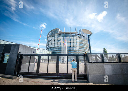 Strasbourg, France - 26 mai 2019 : Seniopr man taking photograph grâce à la porte fermée du siège du Parlement européen avec les pays de l'Union européenne drapeaux flottant - Ciel bleu clair en arrière-plan horizontal image Banque D'Images