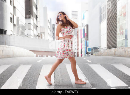 Jeune femme crossing road sur zebra crossing Banque D'Images