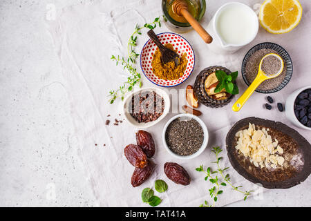 Flt laïcs de super-aliments - miel, les dates, le lait, le curcuma, le citron, les noix et chia sur un fond blanc. La cuisson des aliments sains concept. Banque D'Images