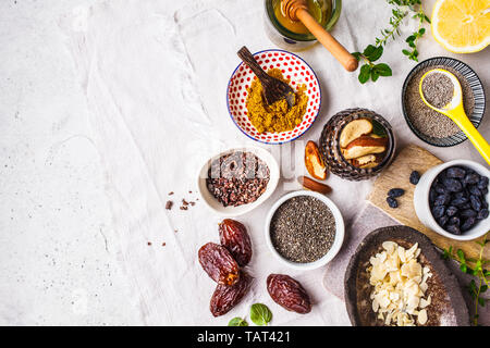 Flt laïcs de super-aliments - miel, dates, curcuma, citron, noix et chia sur un fond blanc. La cuisson des aliments sains concept. Banque D'Images