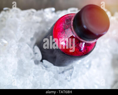 Close-up rouge frais jus en bouteille de plastique dans le circuit de refroidissement de la glace. Banque D'Images