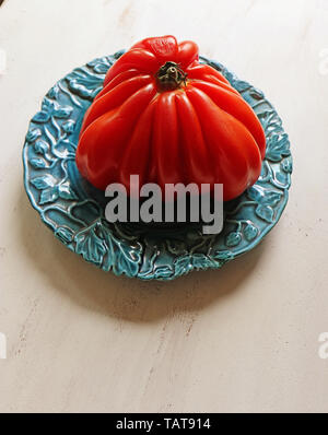 Tomate coeur de boeuf géant sur une plaque bleue Banque D'Images