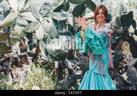 Femme, vêtu d'un costume Flamenco,pied dans la nature avec une raquette à l'arrière, paumes touchant Banque D'Images