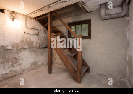 Sous-sol vide abandonné dans ancien bâtiment industriel avec peu de lumière et un escalier en bois Banque D'Images