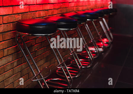 Tabourets de bar au comptoir dans neon light. chaise en cuir au bar Banque D'Images