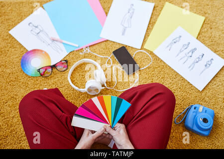 View of female designer avec des couleurs du nuancier assis sur le plancher tout en travaillant plus de mode nouvelle collection at home Banque D'Images