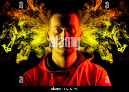 Un adulte guy est hâte in hoodie surlignés en jaune et rouge sur les côtés avec un sourire sur un fond noir motif isolé avec de colo Banque D'Images