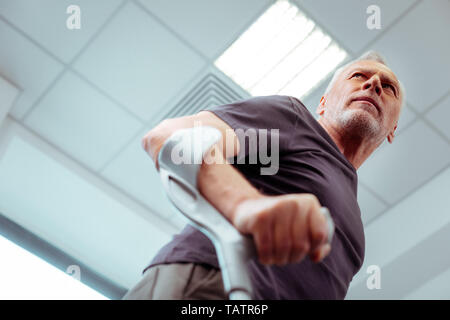 L'équipement spécial. Low angle d'un homme agréable, à l'aide de l'équipement tout en essayant de marcher Banque D'Images