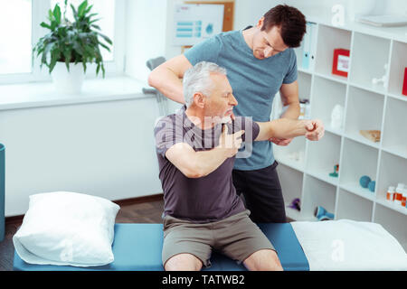 Comment vous sentez-vous. Vue de dessus d'un beau jeune homme debout derrière son patient tout en effectuant un massage pour lui Banque D'Images