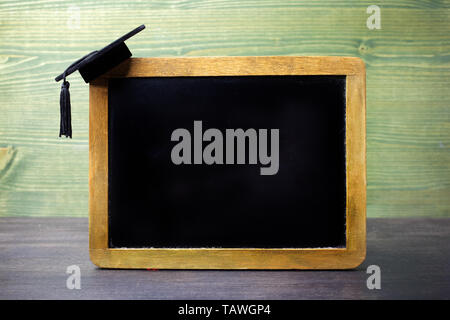 Tableau noir avec une graduation cap accroché à l'angle Banque D'Images