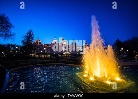 Fontaine illuminée devant l'entrée de Disneyland Paris. Disney Hôtel, Disneyland Hôtel au crépuscule à l'heure bleue. Eau Banque D'Images