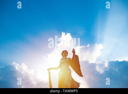 Silhouette d'angel statue sculpture à la lumière du soleil qui brille derrière nuage blanc avec fond de ciel bleu Banque D'Images