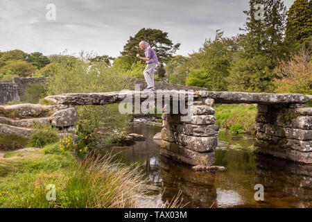 Homme âgé traversant le pont Battant médiévale à Postbridge, Dartmoor, Devon, UK Banque D'Images