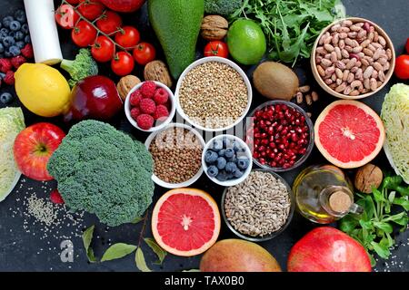 Concept d'aliments sains. L'alimentation végétarienne et végétalienne : légumes, fruits, graines et légumineuses sur fond sombre. Vue d'en haut. Banque D'Images