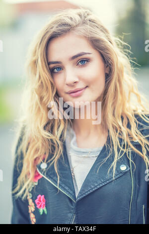 Portrait of attractive blonde fille avec de longs cheveux bouclés et les yeux bleus. Banque D'Images