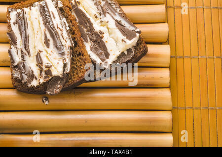 Sandwich avec pain de blé noir grossier et sweet curd et chocolat noir sur un stand de bambou et de bambou serviette. Délicieux petit déjeuner santé simple en e Banque D'Images