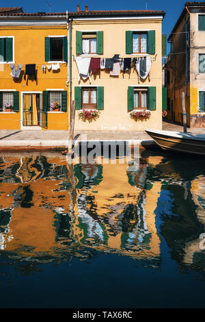 Blanchisserie sèche sur les façades de maisons colorées avec réflexion dans canal, Burano, Venise, Italie Banque D'Images