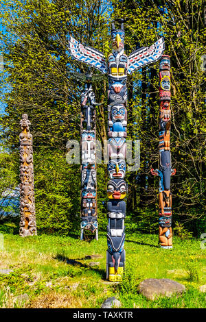 Les Totems colorés représentant des symboles religieux et d'art de la côte ouest les peuples autochtones situé dans le parc Stanley à Vancouver, Canada Banque D'Images