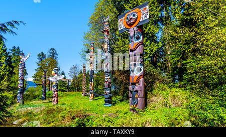 Les Totems colorés représentant des symboles religieux et d'art de la côte ouest les peuples autochtones placés dans le parc Stanley à Vancouver, Canada Banque D'Images